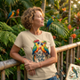 A woman in a tropical garden with parrots, wearing the Talk Birdie to Me Hawaiian t-shirt