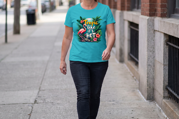 A woman striding down a city sidewalk in the Tropic Like It's Hot flamingo tee