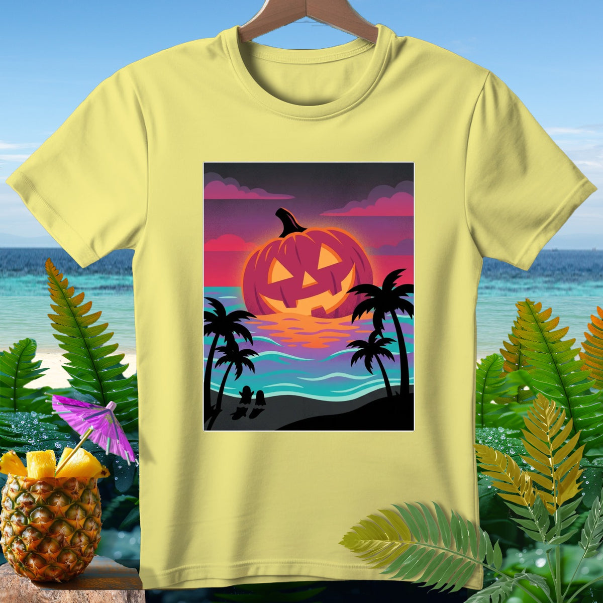Light yellow t-shirt with a graphic of a jack-o'-lantern sunset over a beach scene.