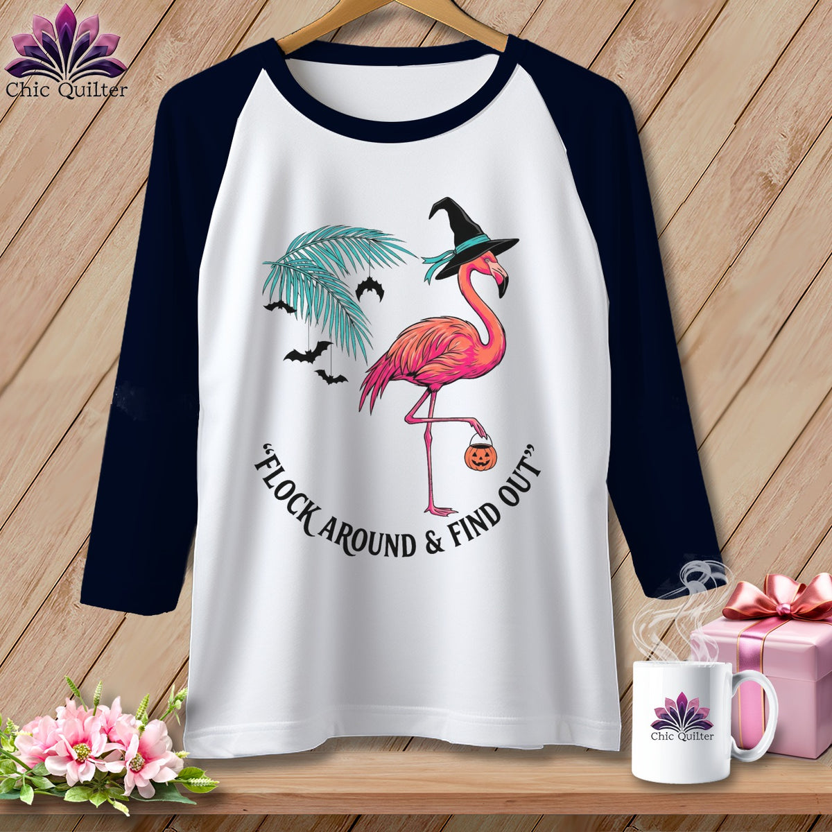 White t-shirt with navy sleeves featuring a flamingo in a witch hat and text.