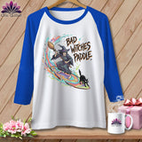 White and blue raglan t-shirt with a witch and black cat graphic that reads 