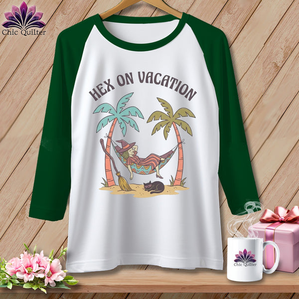 White t-shirt with green sleeves, featuring a witch in a hammock with text "Hex on Vacation."