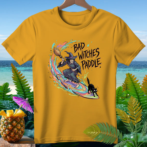 Yellow t-shirt with a witch surfing on a broom and black cat, text "Bad Witches Paddle".