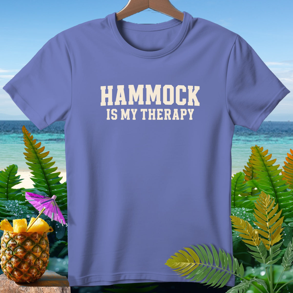 Periwinkle t-shirt with "HAMMOCK IS MY THERAPY" text, tropical background.
