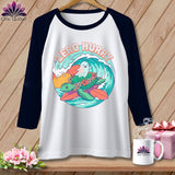 White raglan shirt with a graphic of a turtle and ghost surfing on a wave.