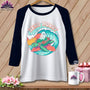 White raglan shirt with a graphic of a turtle and ghost surfing on a wave.