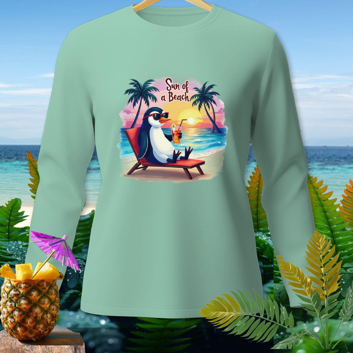 Mint green long-sleeve shirt with a penguin on a beach chair and the text "Sun of a Beach."