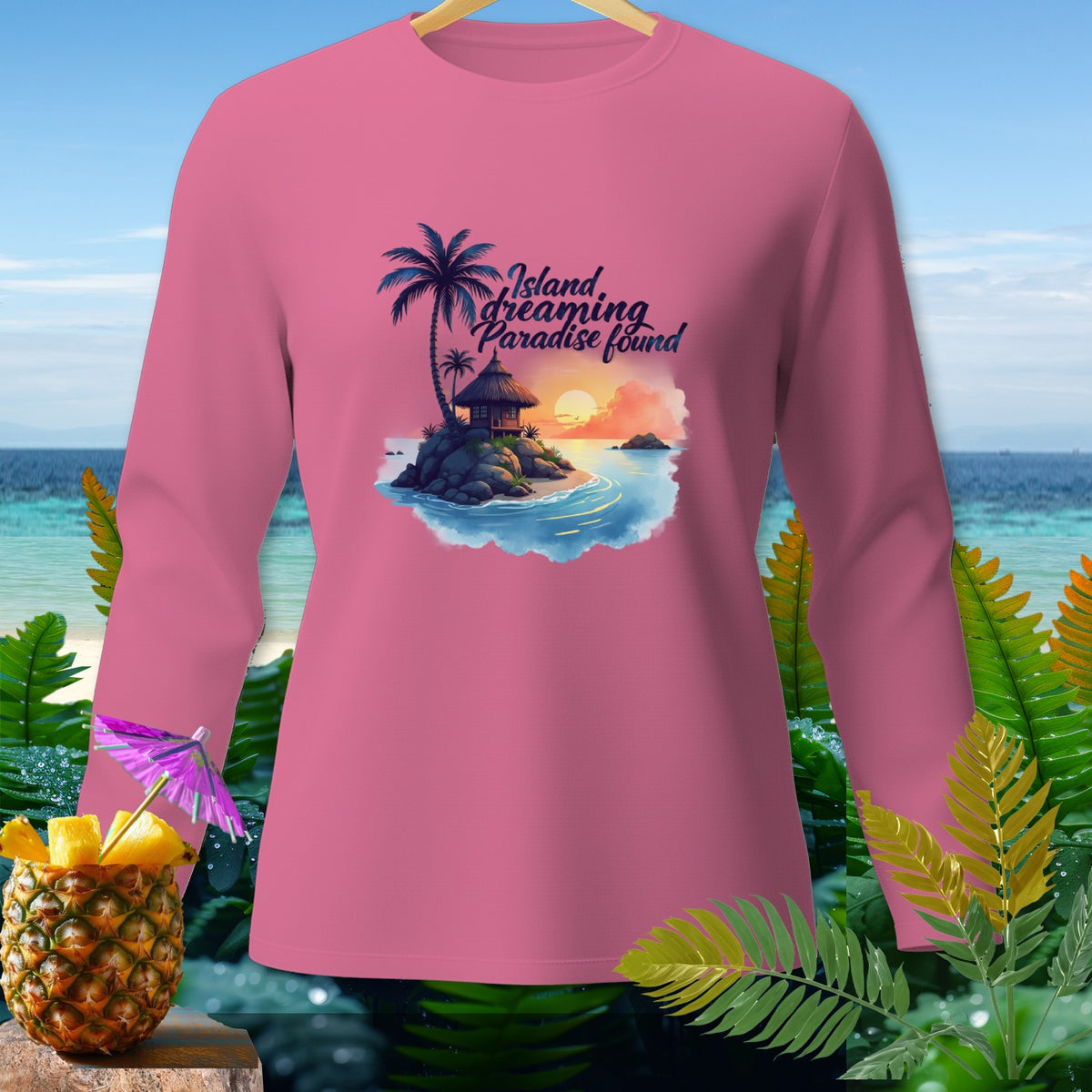 Pink long sleeve shirt with tropical island graphic and text "Island dreaming, paradise found".