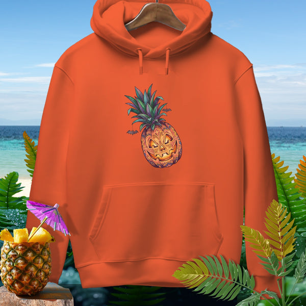 Orange hoodie with jack-o'-lantern pineapple graphic and bats on beach background.