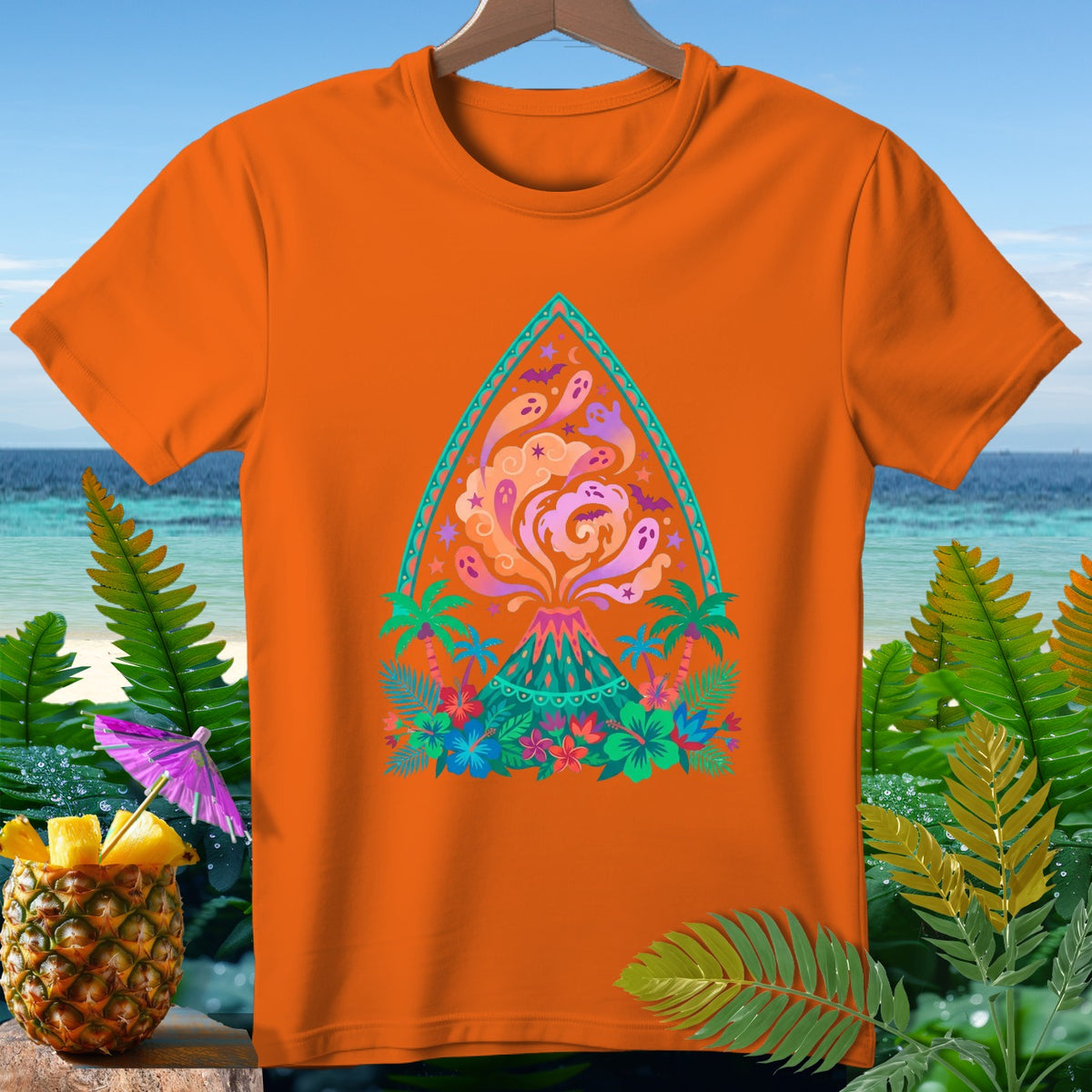 Orange t-shirt with a colorful graphic of a volcano, ghosts, bats, and tropical foliage.