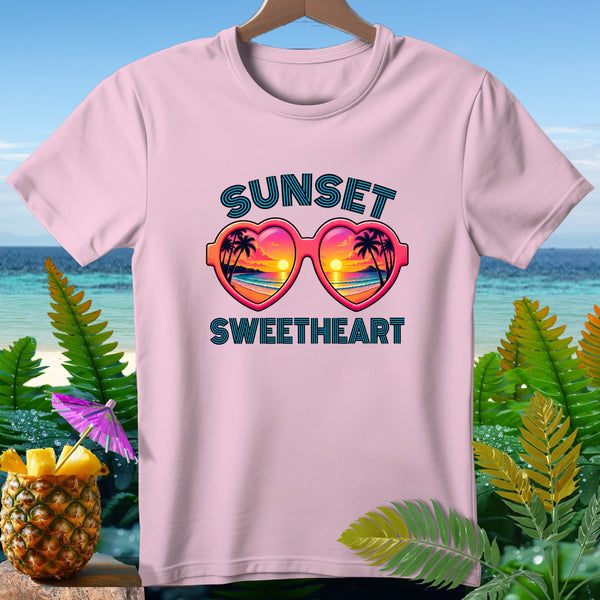 Pink t-shirt with heart-shaped sunglasses reflecting a beach sunset, text "Sunset Sweetheart".