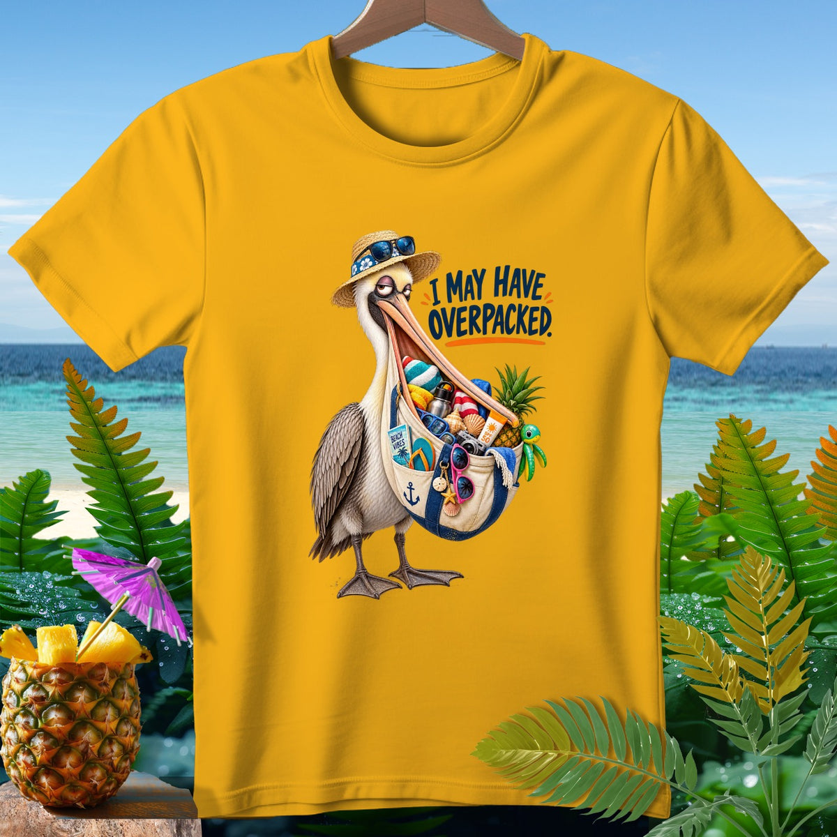 Yellow t-shirt with a pelican holding a bag full of beach items. "I MAY HAVE OVERPACKED."