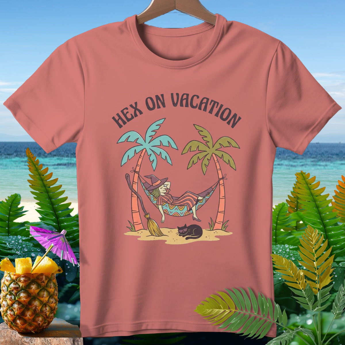T-shirt with witch in hammock, broom, cat, and "Hex on Vacation" text.