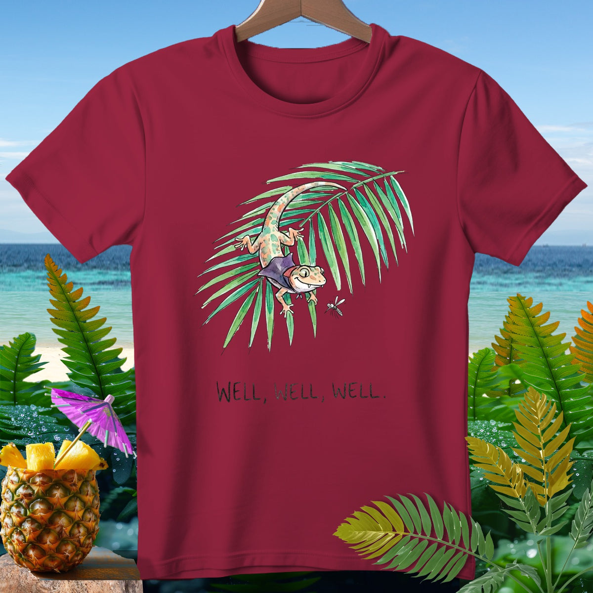 Maroon t-shirt with a gecko on a palm frond, text reads "WELL, WELL, WELL."