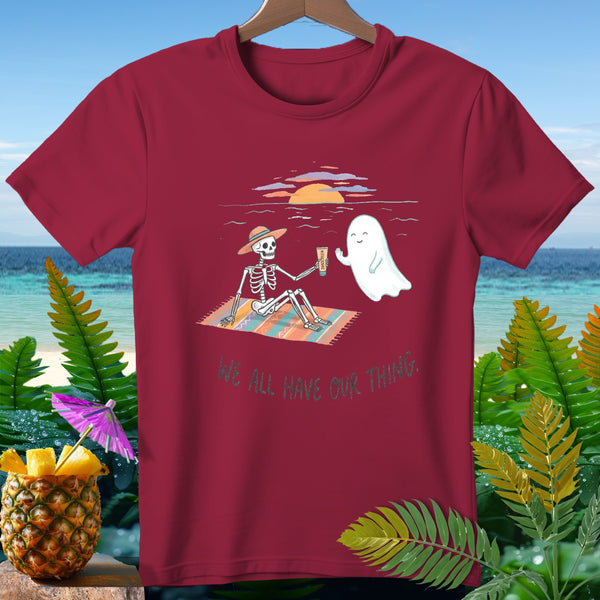 T-shirt with skeleton and ghost on a beach blanket, text "we all have our thing."