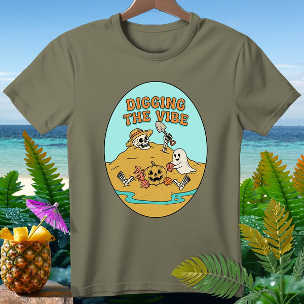 Olive green t-shirt with oval graphic: skeleton, ghost, pumpkin, and text "Digging The Vibe".