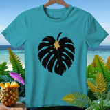 Teal t-shirt with black monstera leaf print, tropical background.