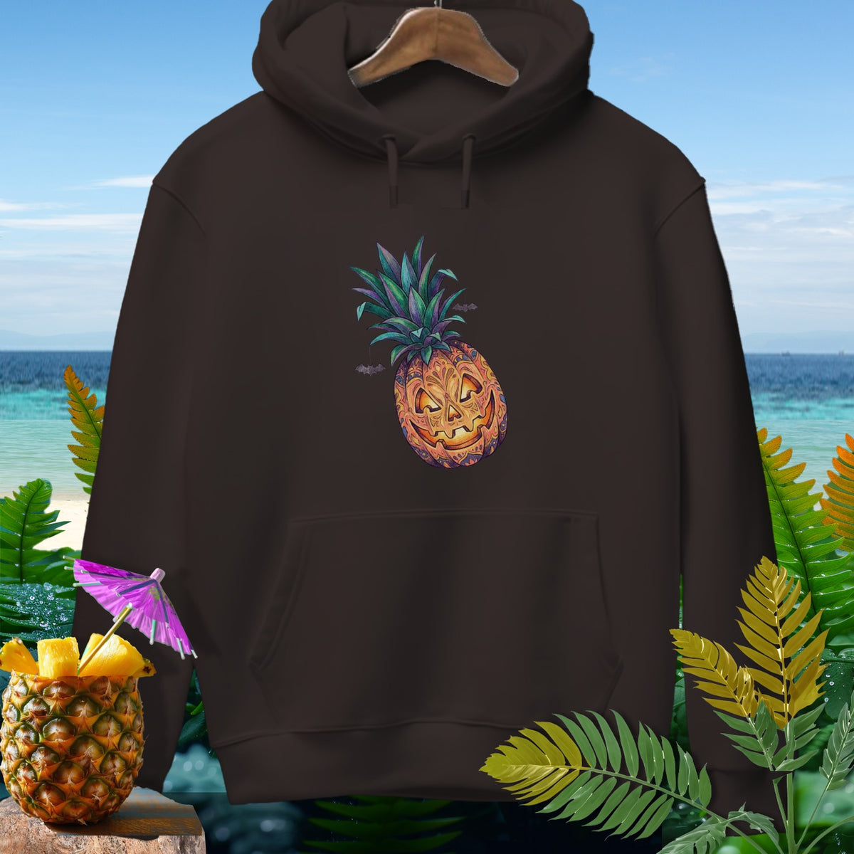 Brown hoodie with a Halloween pineapple graphic and a beach background.