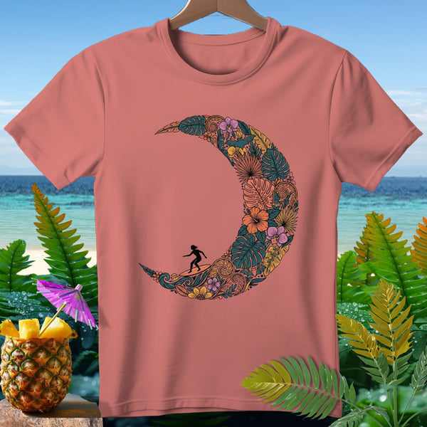 Coral t-shirt with a crescent moon design filled with tropical leaves and flowers and a surfer.