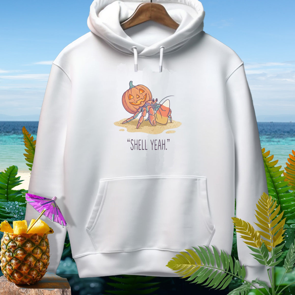White hoodie with a graphic of a hermit crab, a jack-o'-lantern, and candy corn with text "SHELL YEAH."