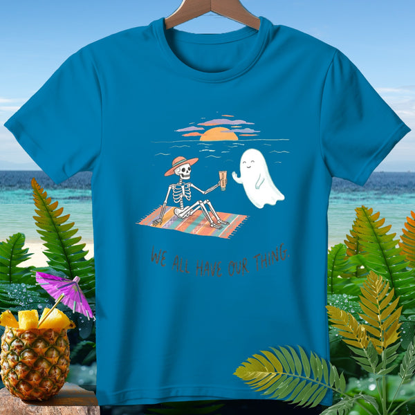 Skeleton and ghost on beach blanket, text "WE ALL HAVE OUR THING."