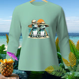 Light green long sleeve shirt with two lizards wearing hats on a beach.