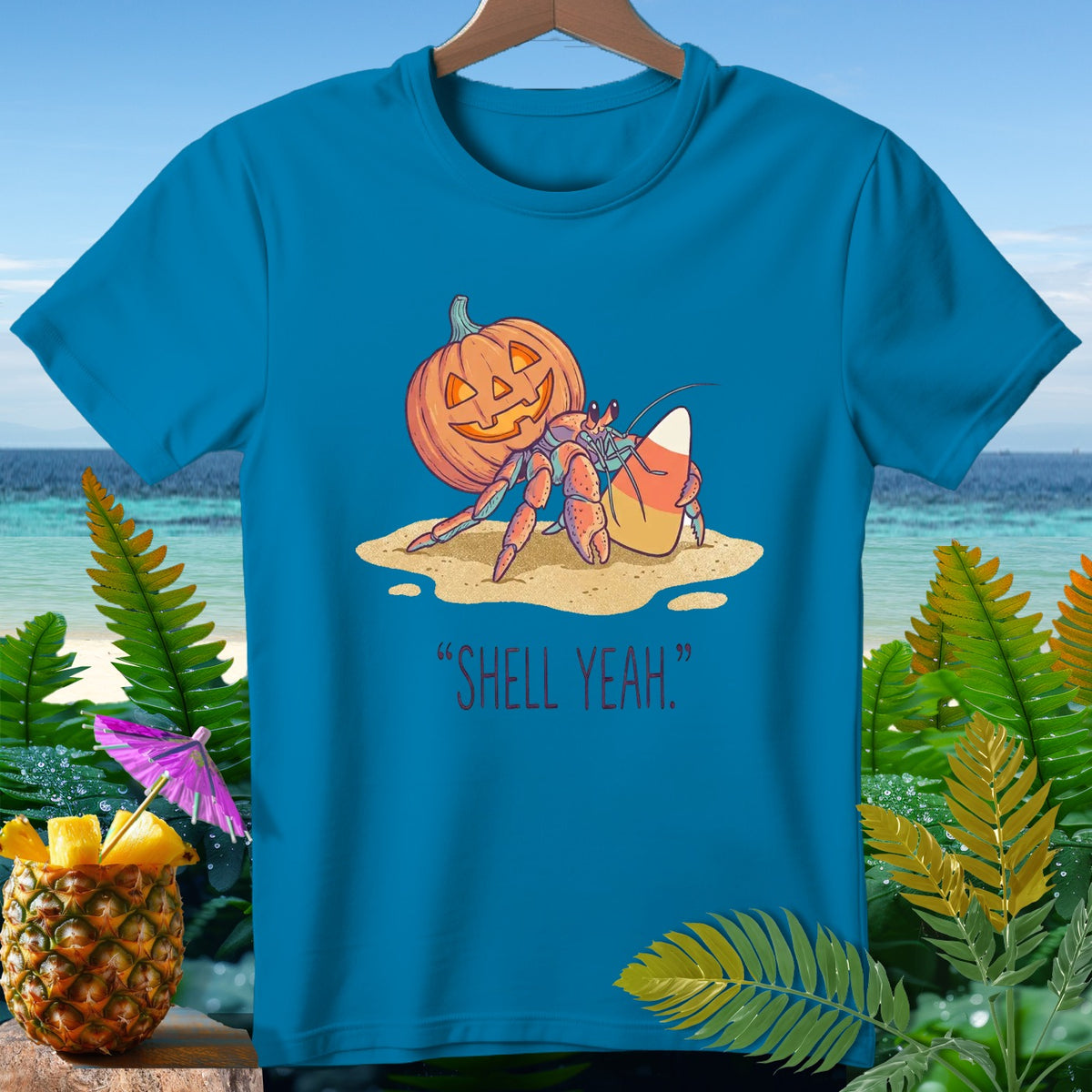 Hermit crab with pumpkin and candy corn on sand, "SHELL YEAH." text.