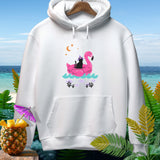 White hoodie with black cat on pink flamingo float, beach and tropical foliage.