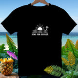 Black t-shirt with white graphic of sun, waves, palm tree, and text 