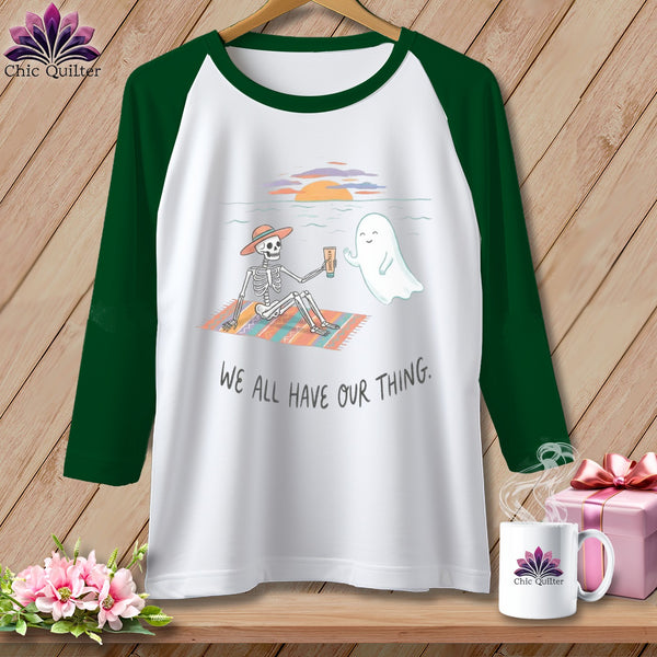 T-shirt with skeleton and ghost on beach, text reads "We all have our thing."