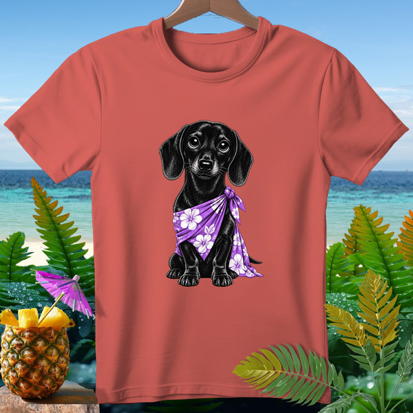 Coral t-shirt with black dachshund wearing a purple floral bandana on a beach background.