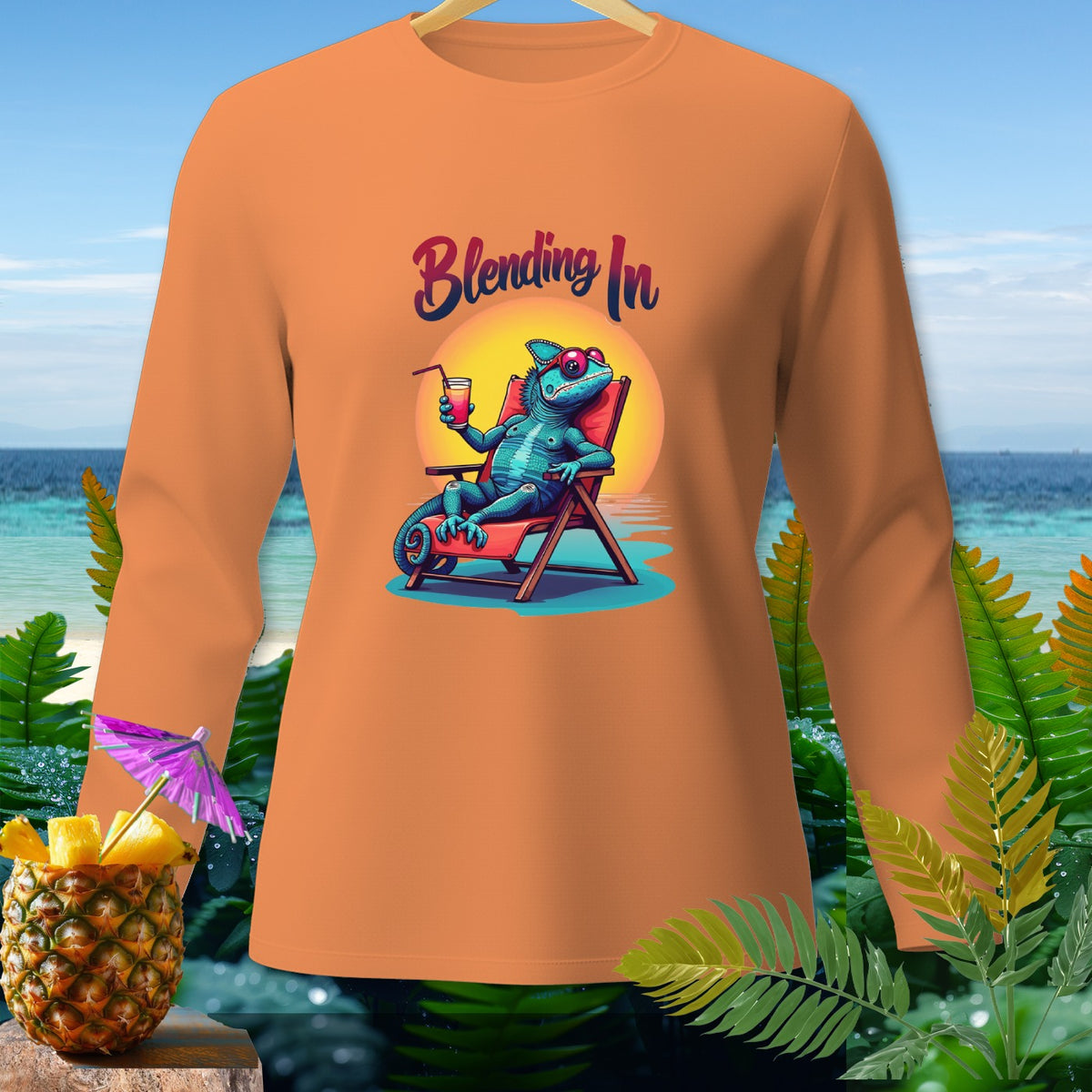 Orange long-sleeve shirt with a blue chameleon on a lounge chair, "Blending In" text, and beach background.