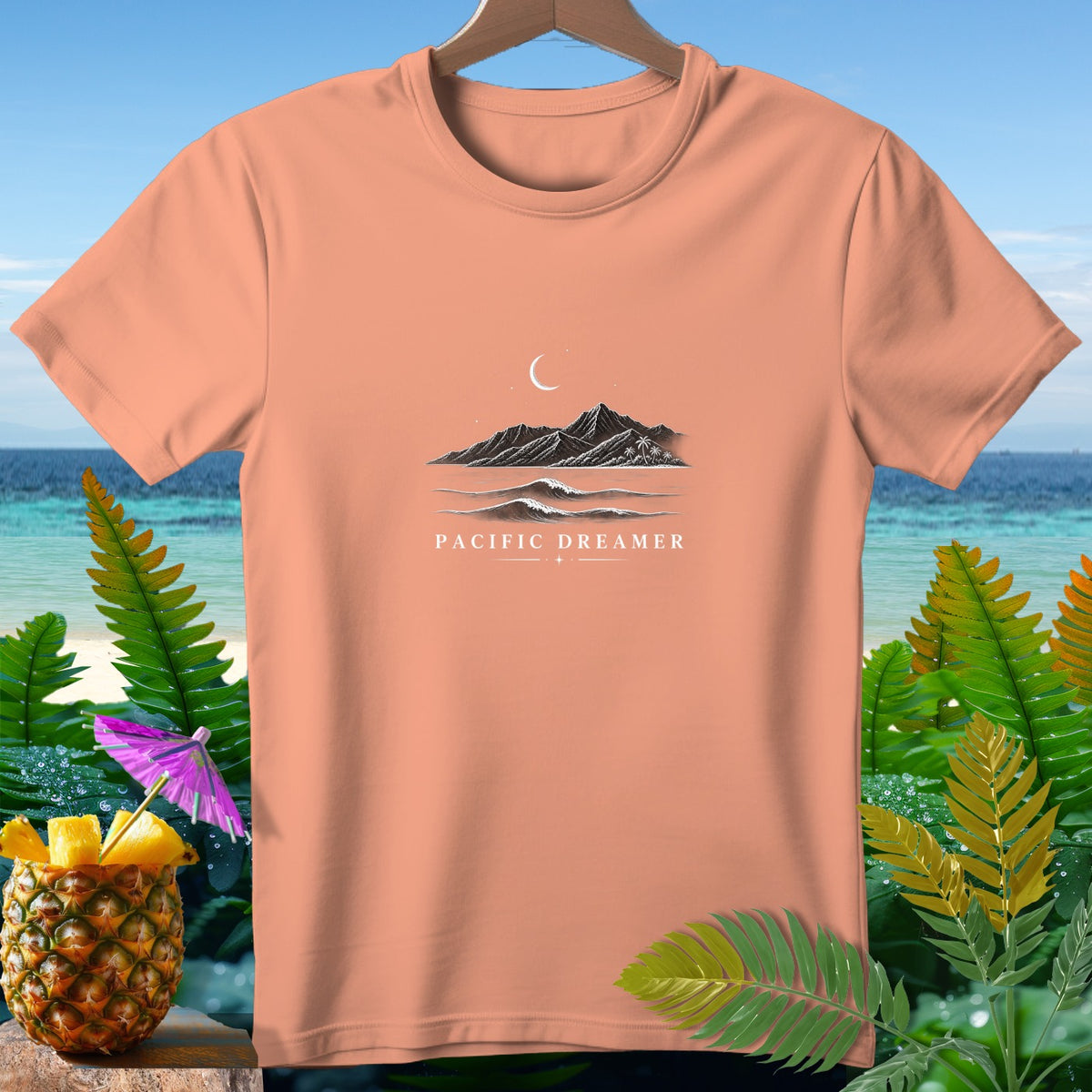 Peach t-shirt with mountains, moon, and waves graphic reading "PACIFIC DREAMER".