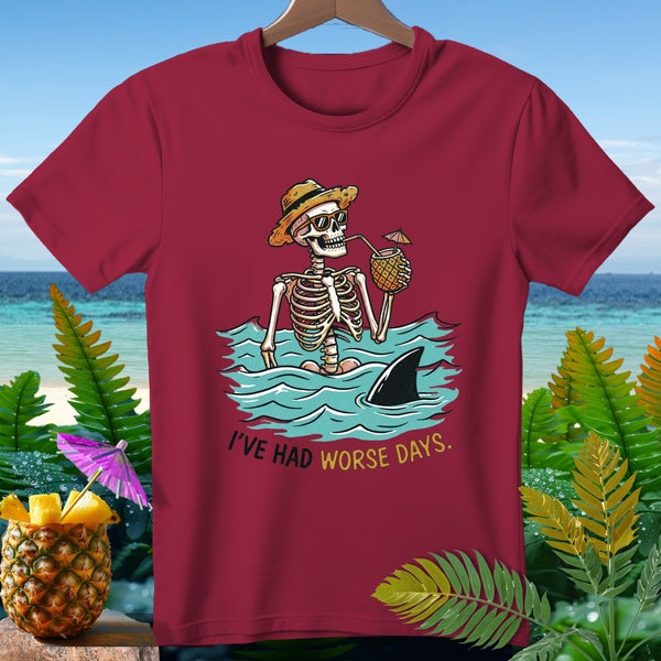 Skeleton in ocean with shark fin, drinking pineapple cocktail. "I'VE HAD WORSE DAYS."