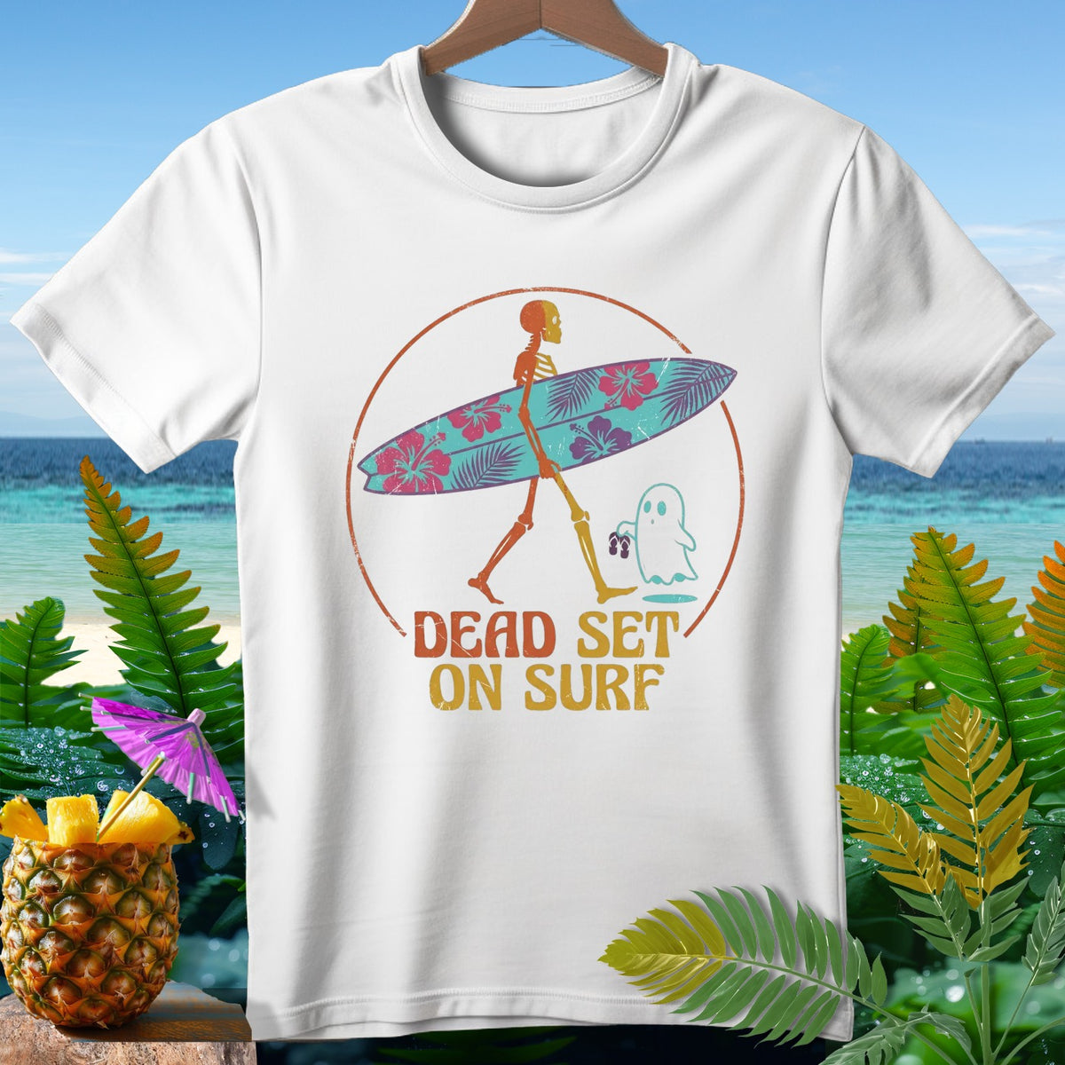 White t-shirt with skeleton carrying surfboard and ghost, text reads "Dead Set On Surf".