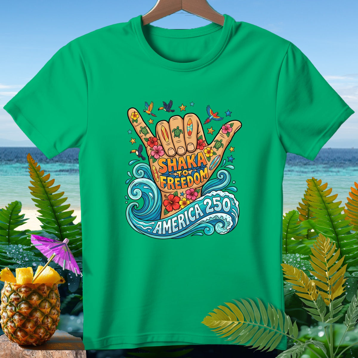 Green t-shirt with "Shaka to Freedom America 250" graphic on hand and tropical elements.