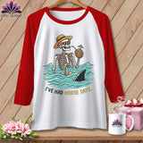 White t-shirt with red sleeves featuring a skeleton in the ocean with a shark fin and text 