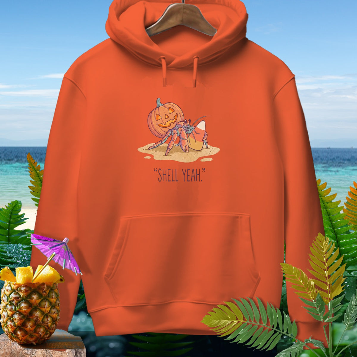 Orange hoodie with a hermit crab, pumpkin, and candy corn graphic that says "SHELL YEAH."
