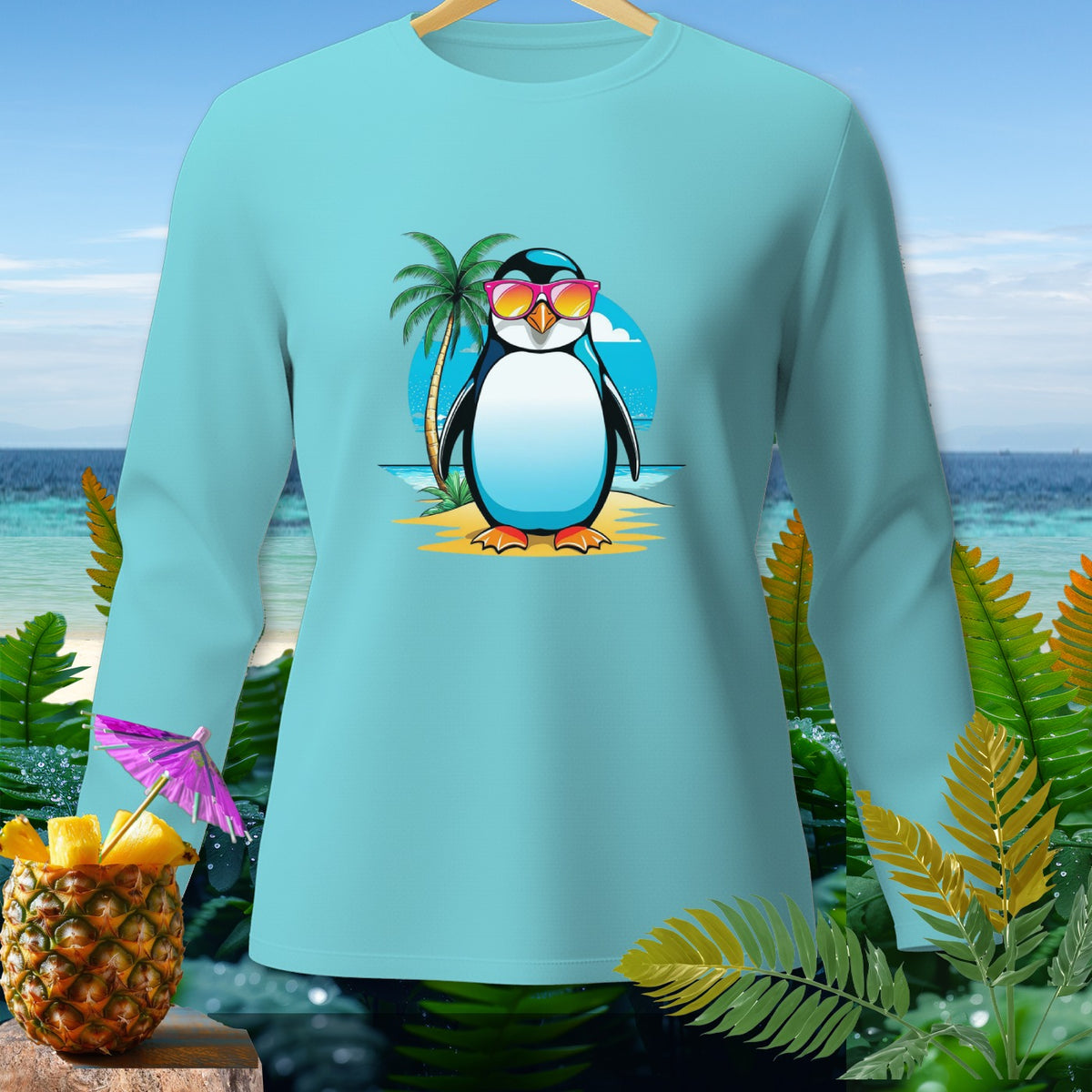 Light blue long-sleeve shirt with a cartoon penguin wearing sunglasses on a beach.