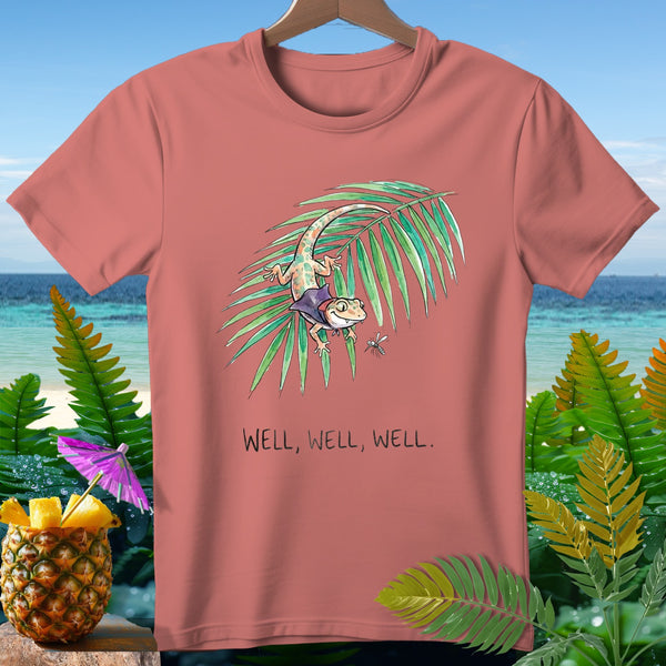 Pink t-shirt with watercolor gecko on palm frond, text "WELL, WELL, WELL."