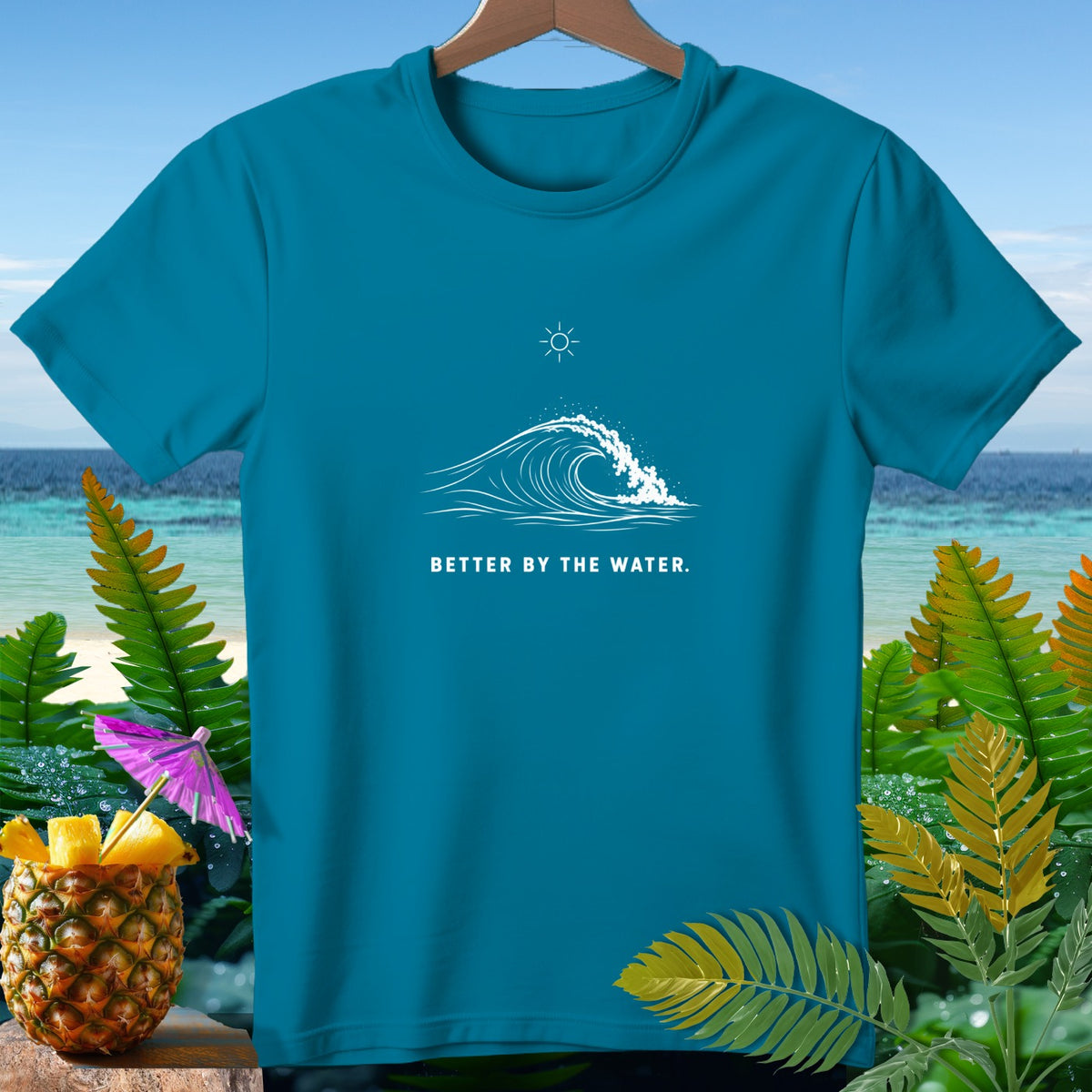 Teal t-shirt with white wave graphic and text "BETTER BY THE WATER".