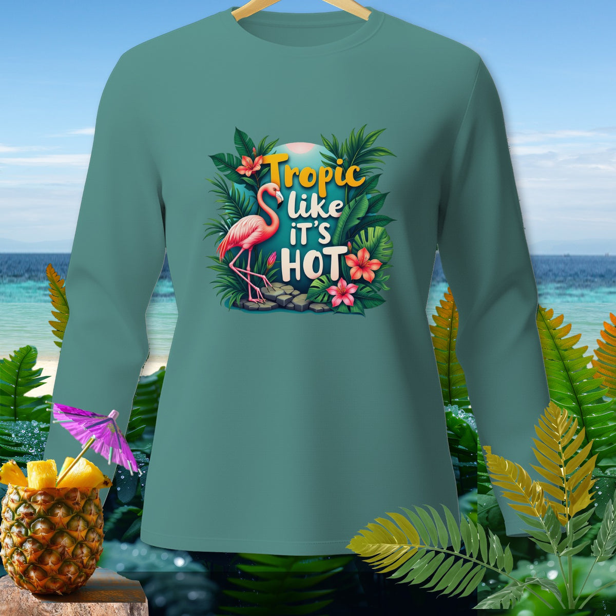 Teal long-sleeve shirt with a flamingo and tropical leaves graphic reading "Tropic like it's HOT".