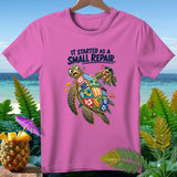 Pink t-shirt with two cartoon sea turtles, one with a patchwork shell, and text.