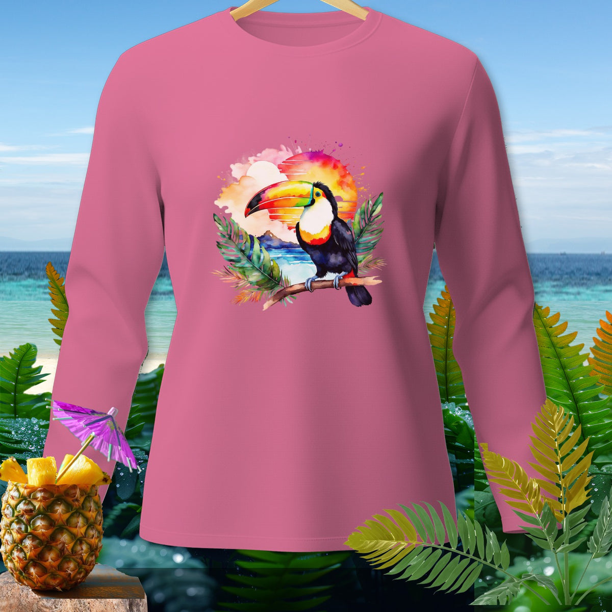 Pink long-sleeve shirt with a watercolor toucan and tropical sunset graphic.