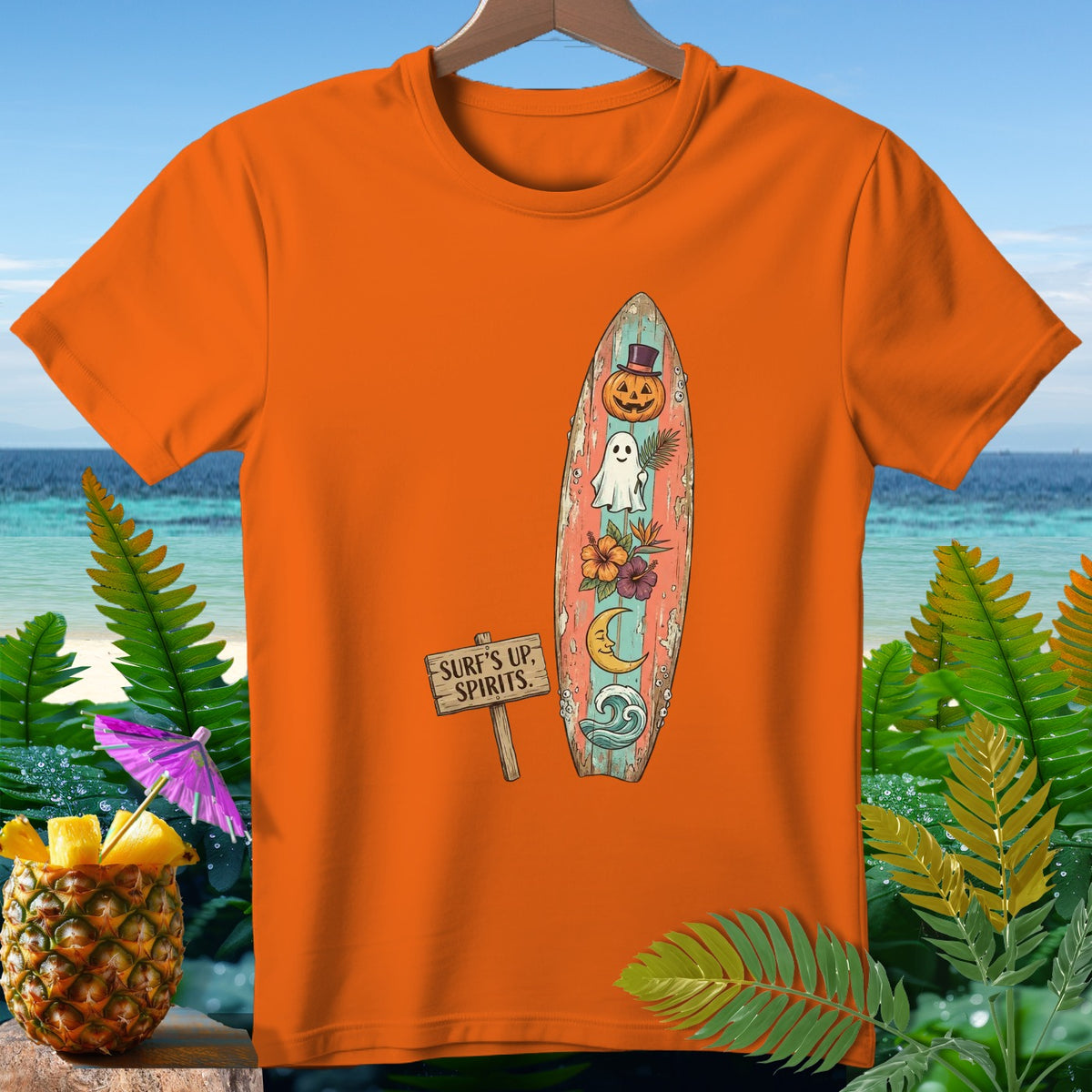 Orange t-shirt with a surfboard graphic featuring a pumpkin, ghost, moon, and flowers.