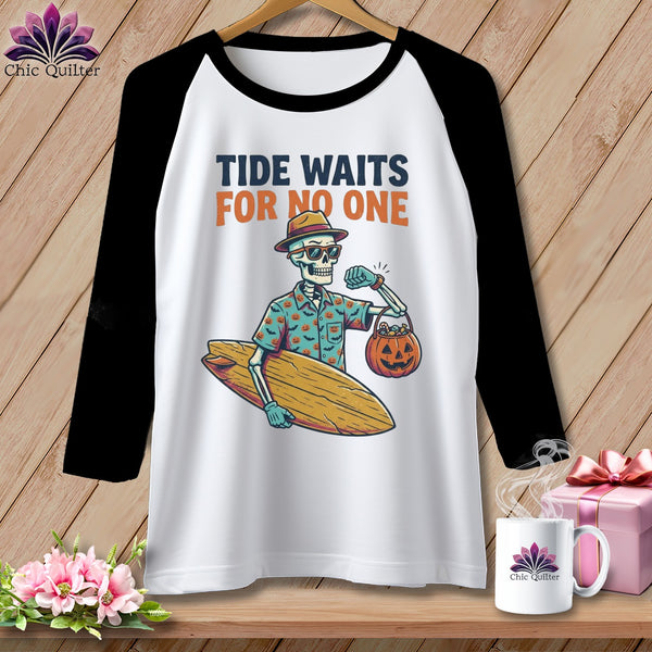 White baseball tee with skeleton holding surfboard and pumpkin bag, "Tide Waits For No One" text.