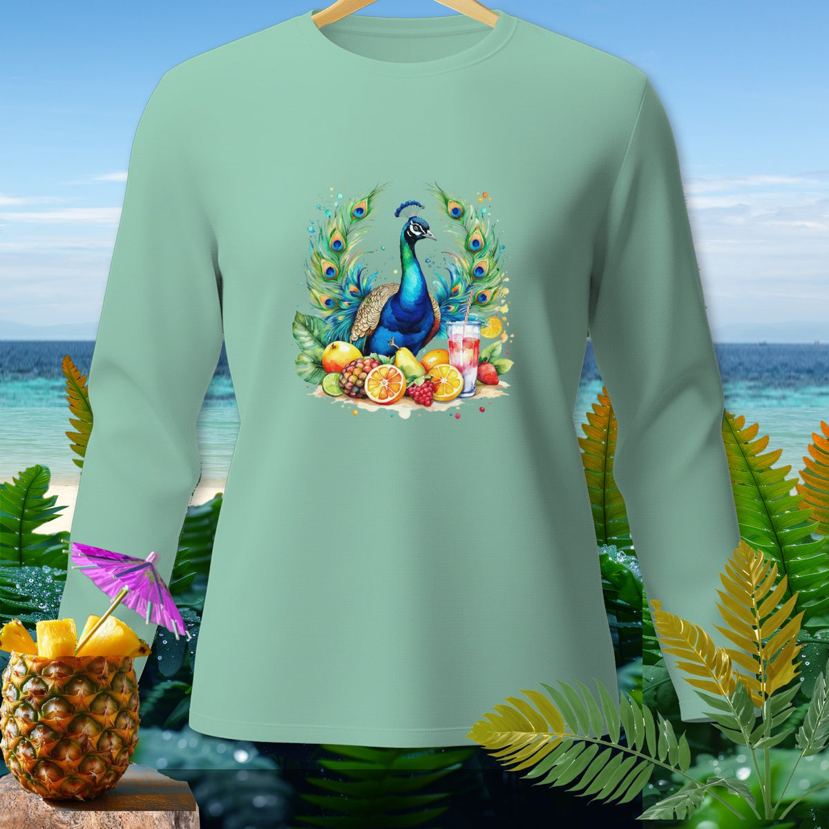 Light teal long-sleeve shirt with a peacock and fruit graphic, set against a beach backdrop.