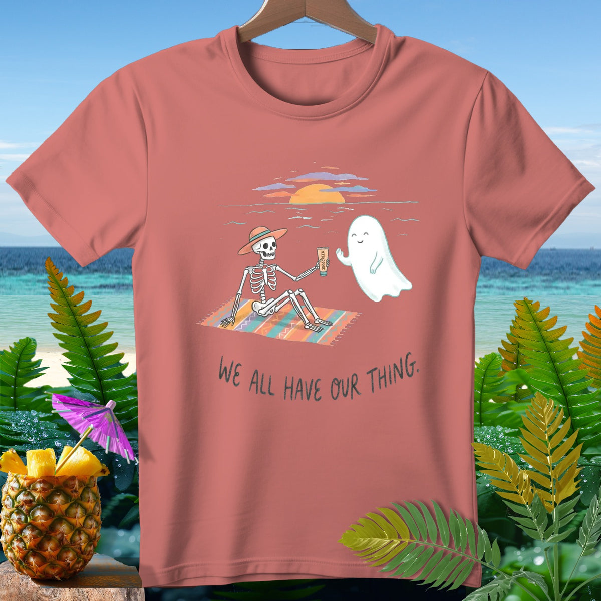 T-shirt with skeleton and ghost on beach with text "We all have our thing."