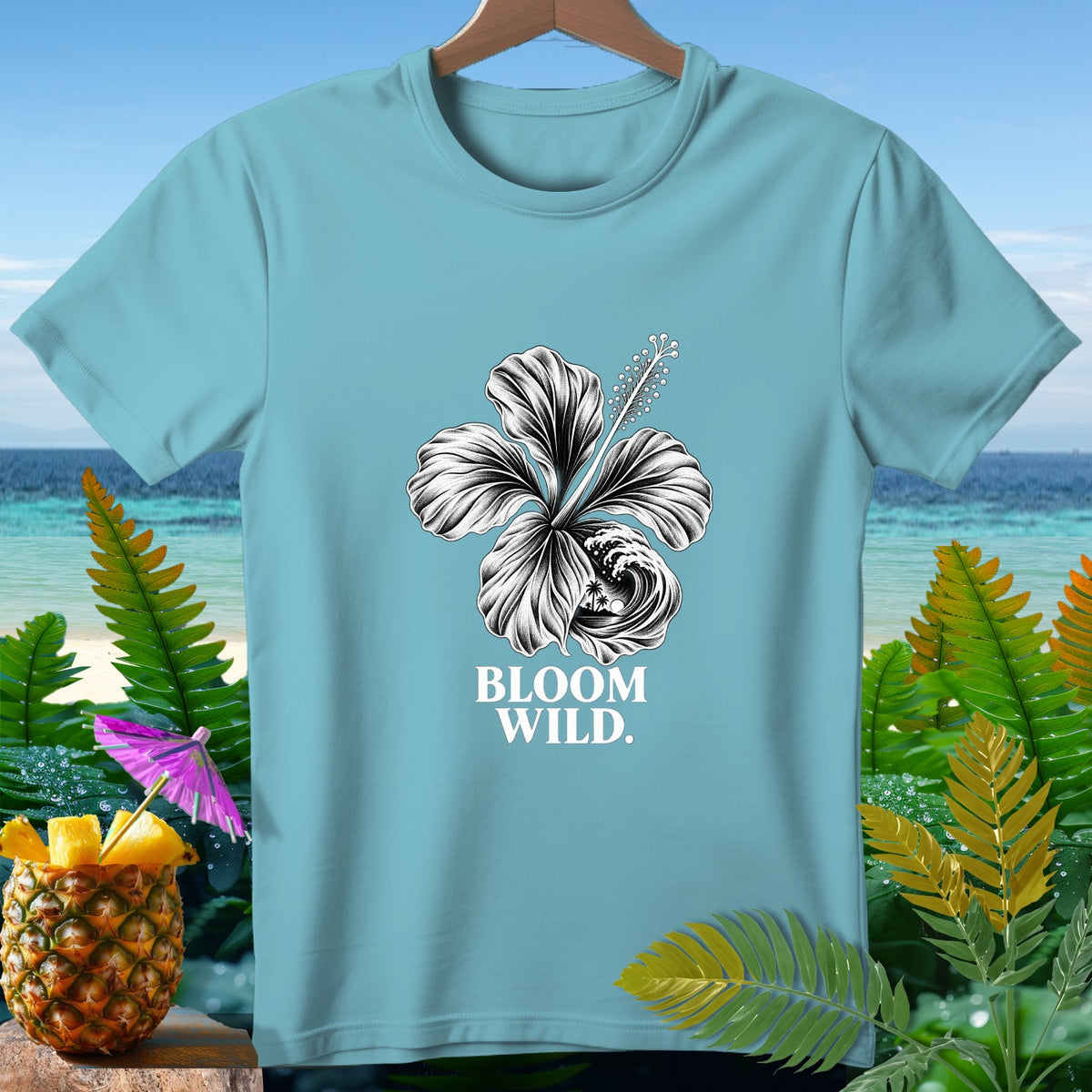Light blue t-shirt with a black and white hibiscus and wave design, text "BLOOM WILD".