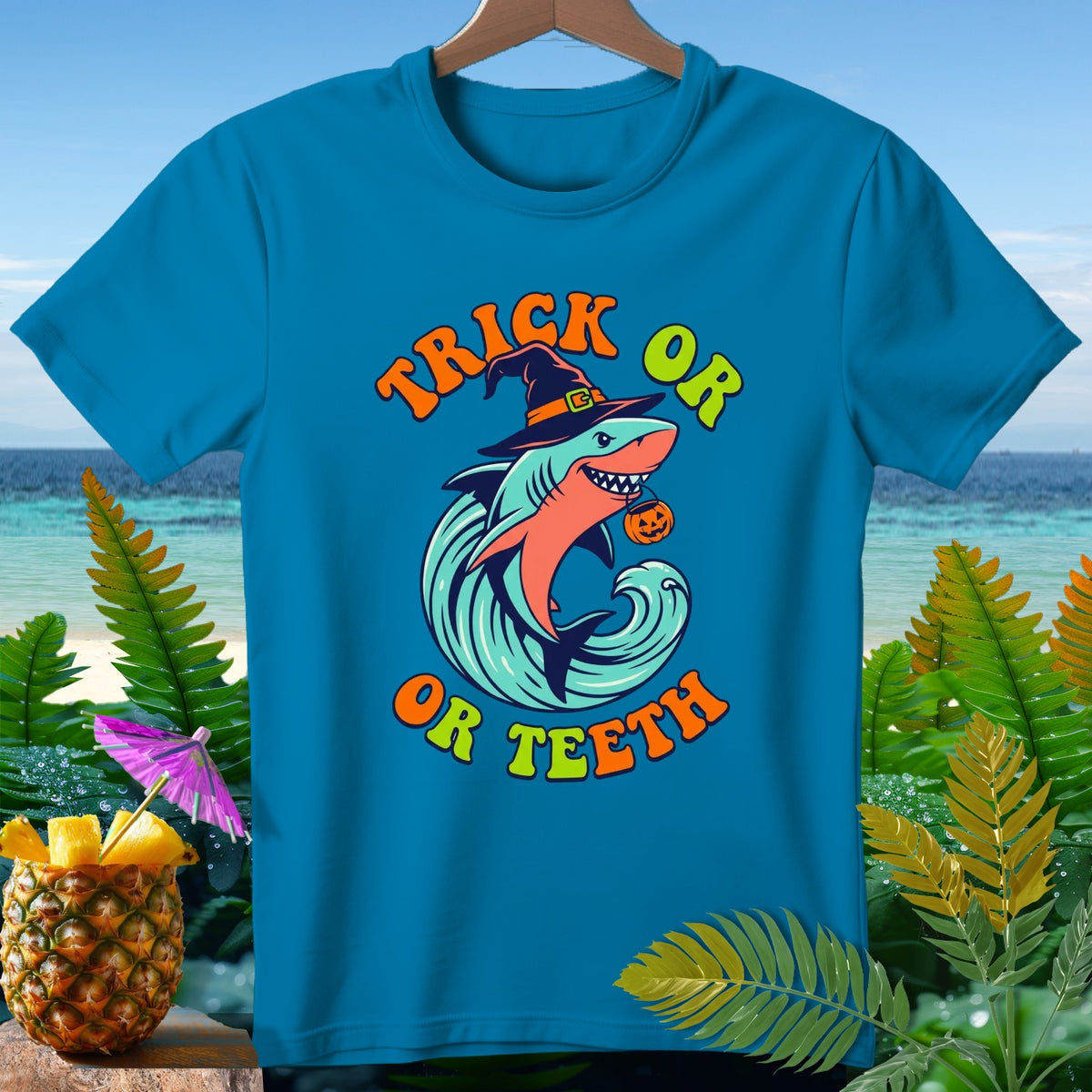 Blue t-shirt with a shark wearing a witch hat and pumpkin, text "Trick or Teeth".
